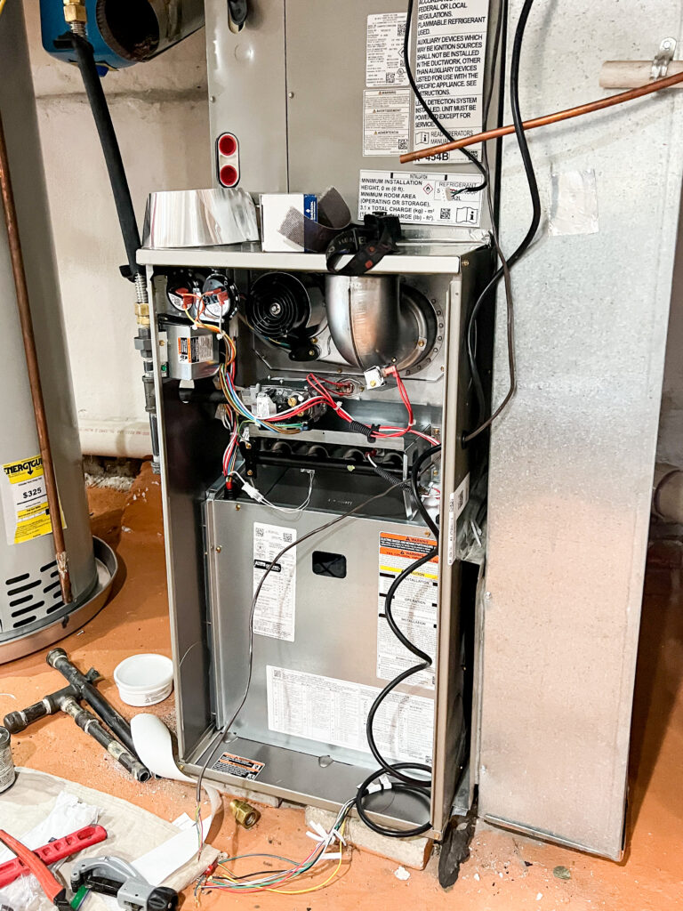 Open furnace system during replacement, showing internal components, wiring, and blower assembly in a Philadelphia basement.