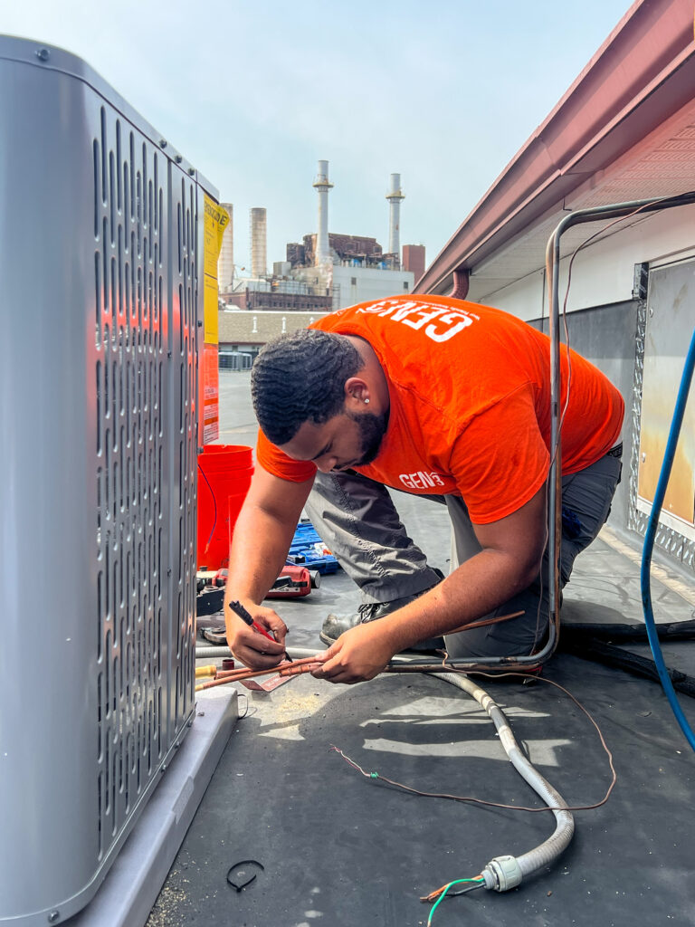 GEN3 Electric & HVAC technician connecting copper refrigerant lines during rooftop AC installation in Philadelphia, ensuring precise and professional setup